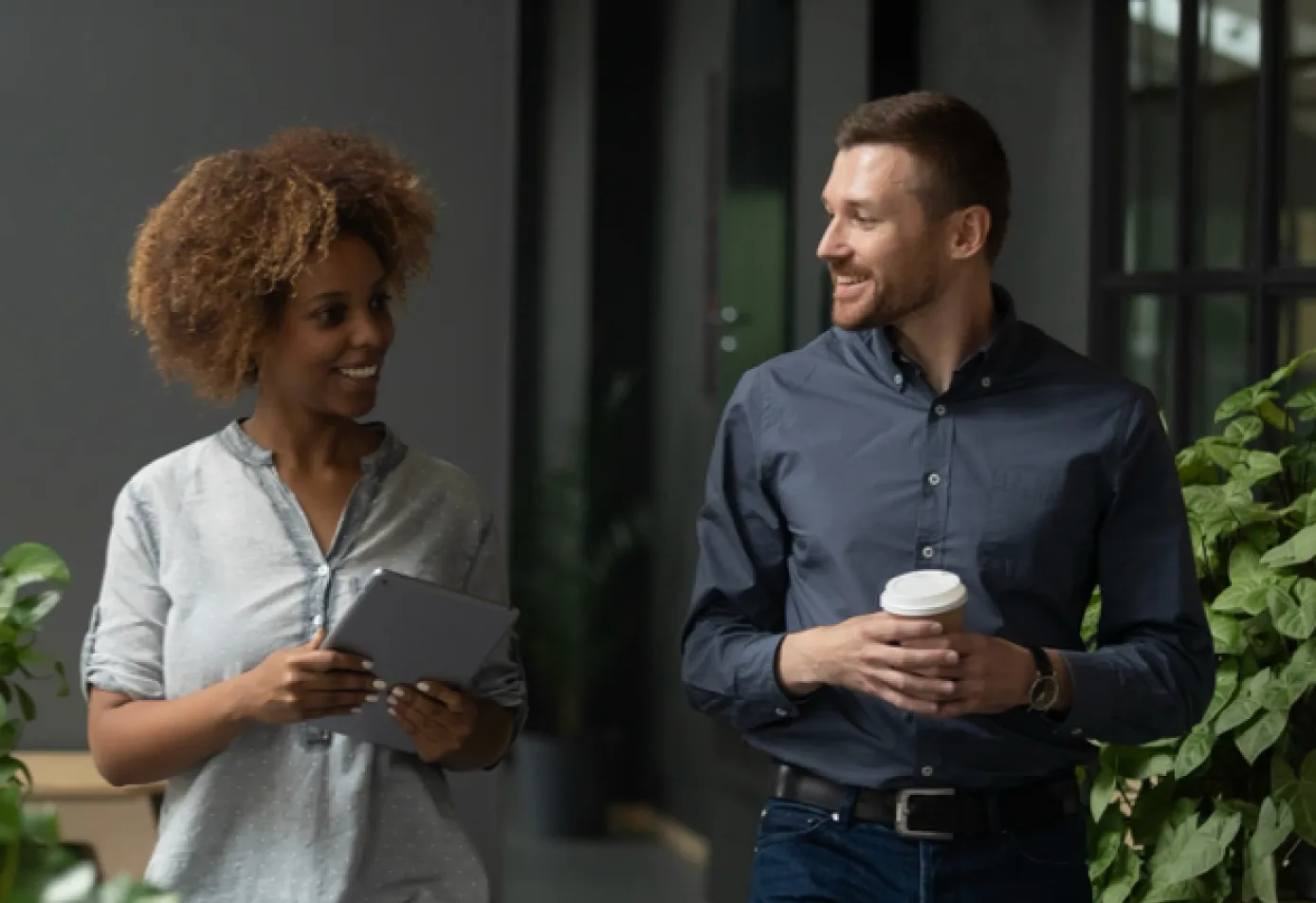black woman and white man talking while walking in office space