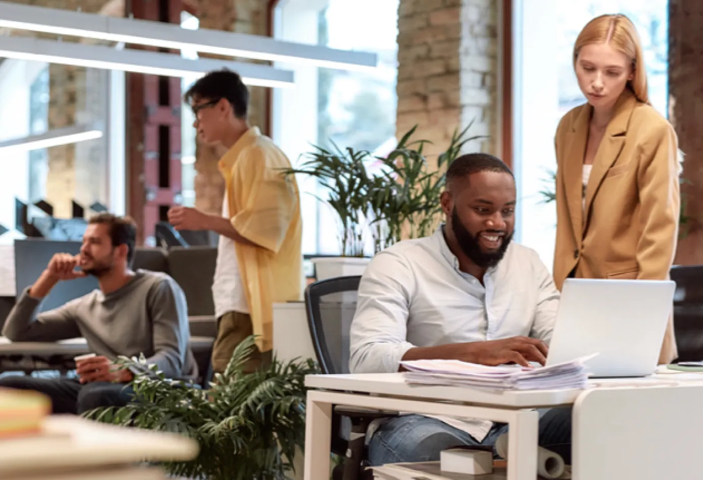 3 men of varying nationalities and one woman working in groups inside of office