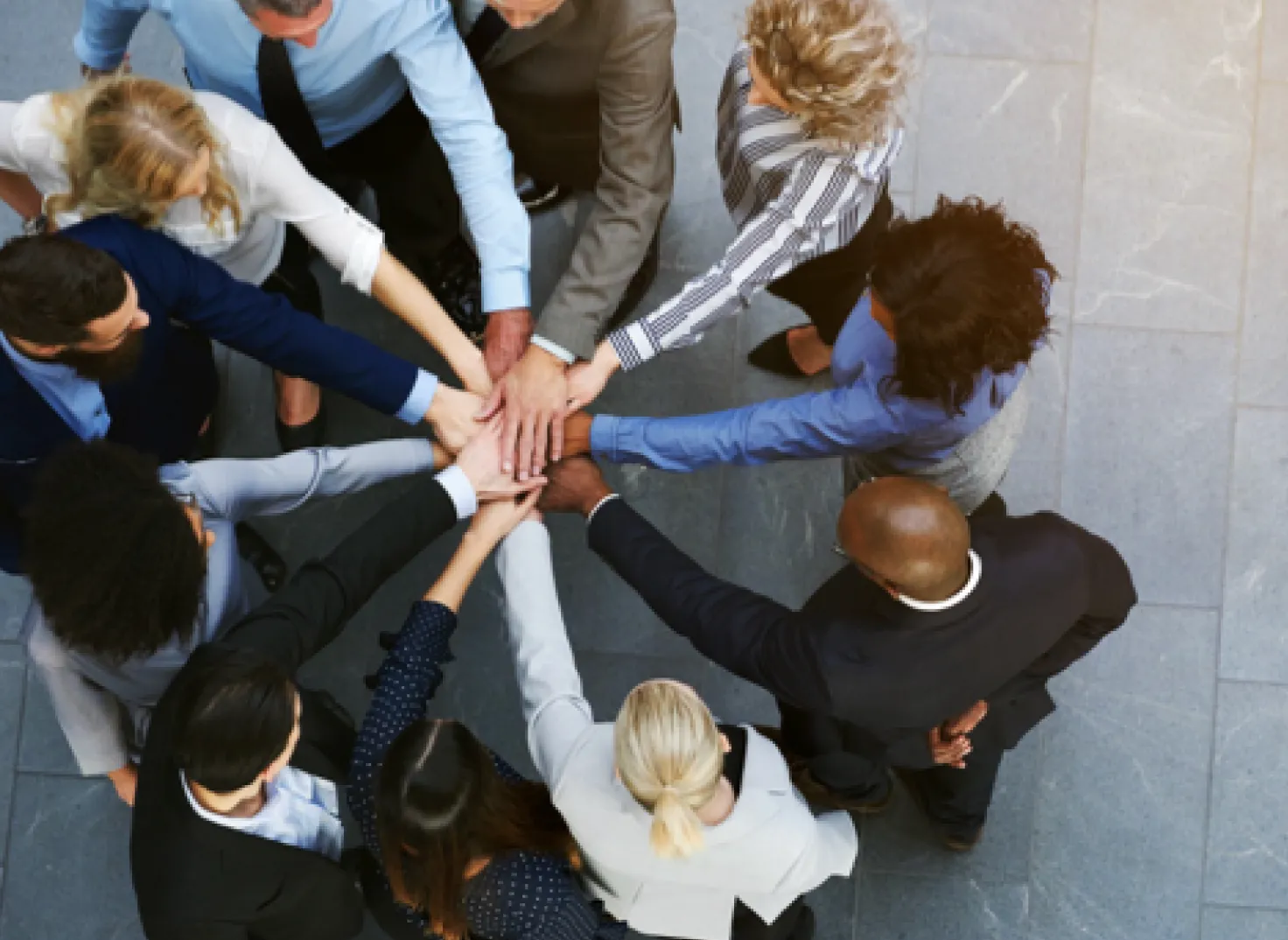 group of multi cultural business professionals with hands together standing outside