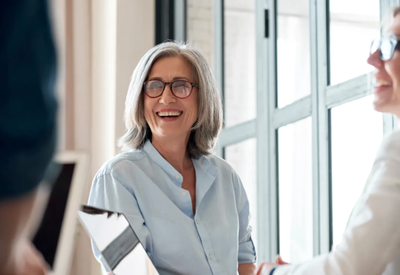 white woman with glasses at office in meeting laughing